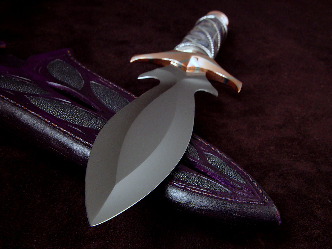 "Amethistine" dagger, obverse side view in 440C high chromium stainless steel blade, diffusion welded copper, nickel silver fittings, sterling silver gallery wire wrap and accents, Amethyst crystal gemstone pommel, hand-carved leather sheath inlaid with black rayskin