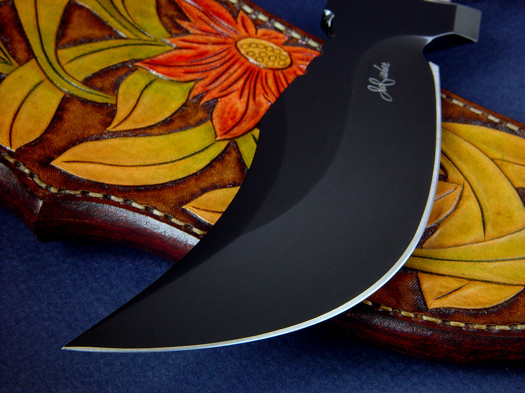 "Flamesteed" obverse side point view in mirror finished, hot blued O1 high carbon tungsten-vanadium tool steel blade, hand-engraved 304 stainless steel bolsters, Bird's Eye Rhyolite gemstone handle, hand-carved, hand-dyed leather sheath