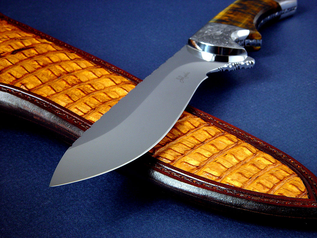 "Golden Eagle" obverse side view in CPM154CM high molybdenum powder metal technology tool steeel blade, hand-engraved 304 stainless steel bolsters, Bicolored Tiger Eye gemstone handle, Caiman skin inlaid in hand-carved leather sheath