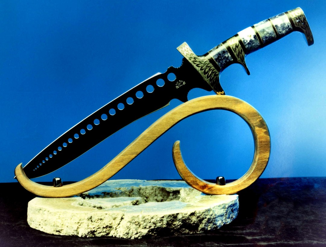 "Treatymaker" in blued 01 high carbon tungsten-vanadium tool steel blade, hand-engraved brass guard, pommel, and subhilt, Scaploite/Sodalite gemstone handle, stand of Goncalo Alves, blued steel, geodic agate base