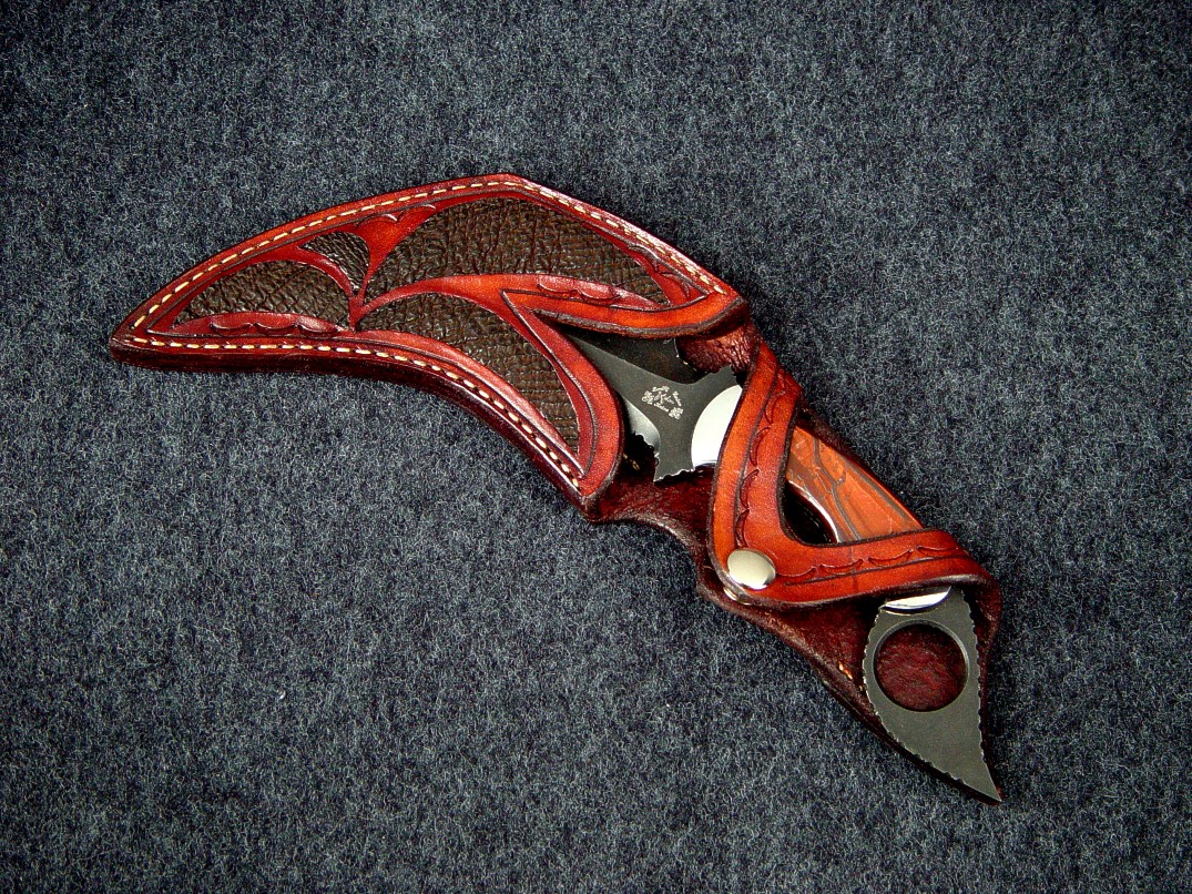 "Triton" double edged kerambit with open handle display type sheath. Knife is blued O-1 tool steel, stainless steel bolsters, Red Tiger eye gemstone handle. Sheath has Cape Buffalo skin inlays