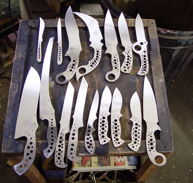 Knives in production in a variety of blade shapes. They're  profiled, roughed in, drilled, and milled, tangs tapered, ready for hollow grinding