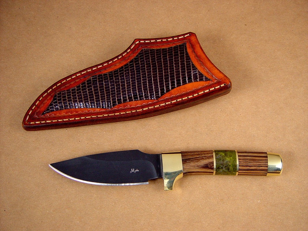 Fine custom handmade knives: "Alamogordo" Obverse side view: O-1 high carbon tungsten-vanadium alloy tool steel blade, bead blasted and hot blued, brass guard, pommel, and fittings, zebrawood hardwood and serpentine gemstone handle, lizard skin inlaid in hand-carved leather sheath