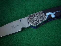 "Gemini" folding knife, obverse side front bolster engraving detail. Engraving design utilizes orbicular pattern and droplet shape exhibited in the gemstone  handle scales.