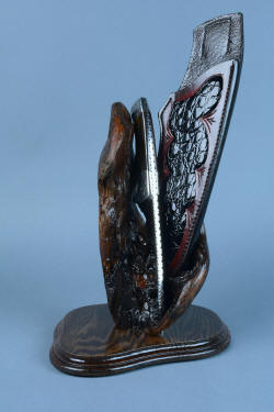 "Golden Eagle" custom knife, in stand view, spine forward. Full filework stands out against the dark burl wood