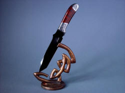 "Tharsis Intense" knife and stand solo. Blade is bold and antiqued patina of bronze echoes hand-carved form